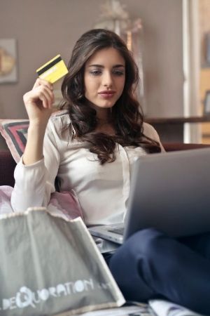 woman holding credit card while browsing computer