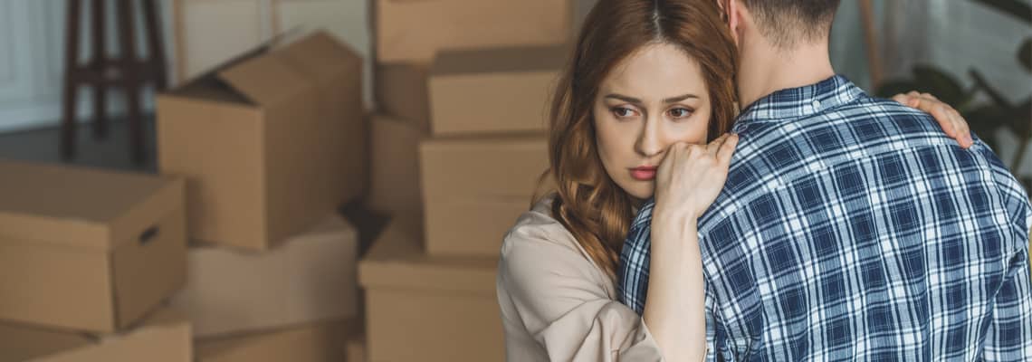 Couple hugging sadly in front of moving boxes